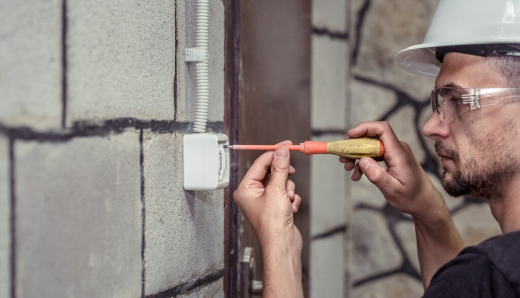 male electrician-technician, connects the equipment with a tool